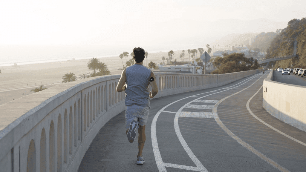 A runner on a coastal road at sunrise, illustrating endurance exercise and how the body fuels athletic performance.